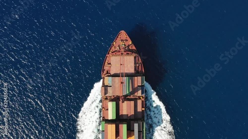 Luftaufnahme eines mit Containern beladenem Frachters in voller Fahrt über blauem Ozean photo