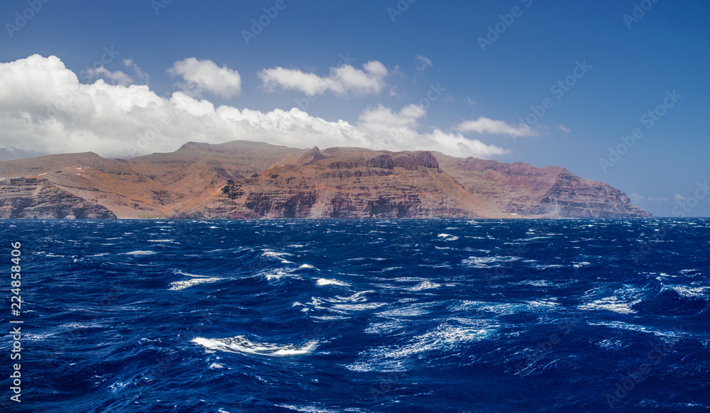 La Gomera island volcanic coastline view with waves and blue sky and clouds, Canary islands, Spain
