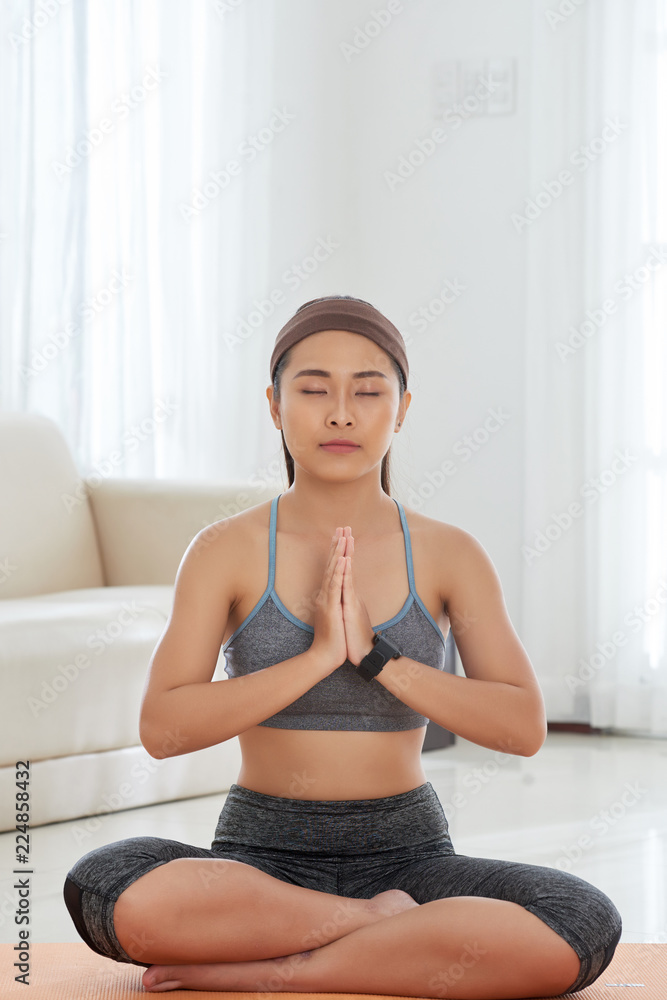 Young Asian woman in sportswear sitting on mat in relaxation and meditating peacefully Young Asian woman in sportswear sitting on mat in relaxation and meditating peacefully