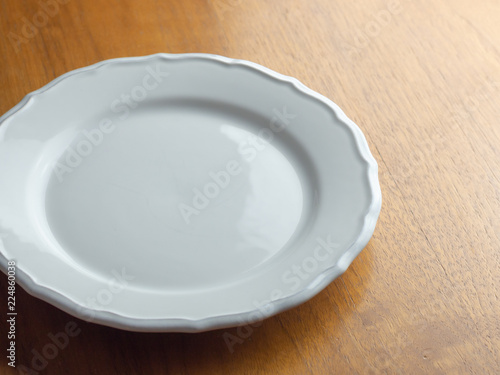 Empty white plate on a wooden table