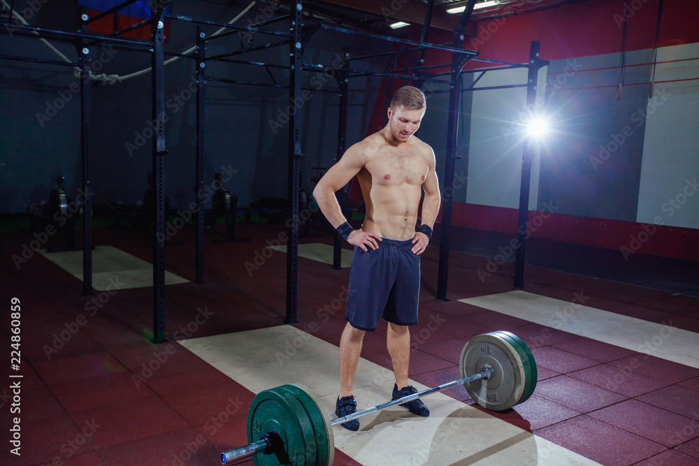 portrait of a muscular man workout with barbell at gym. stands near the bar, resting. portrait of a muscular man workout with barbell at gym. stands near the bar, resting.