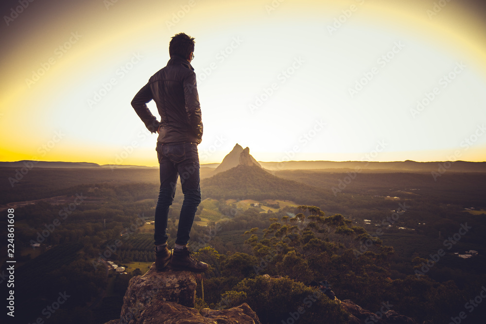 Man standing on cliff above valley - obrazy, fototapety, plakaty 