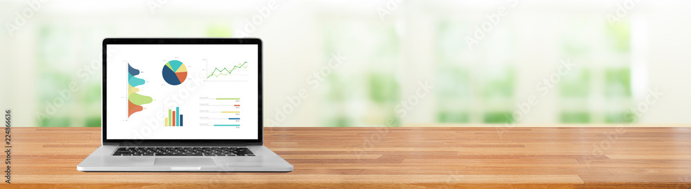 Modern computer with keyboard and mouse on table showing charts and graph against office with windows and green nature indoor background bokeh light, Analysis Business, Statistics Concept. Modern computer with keyboard and mouse on table showing charts and graph against office with windows and green nature indoor background bokeh light, Analysis Business, Statistics Concept.