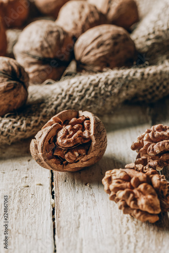 close-up view of whole and cracked walnuts and sackcloth on wooden table