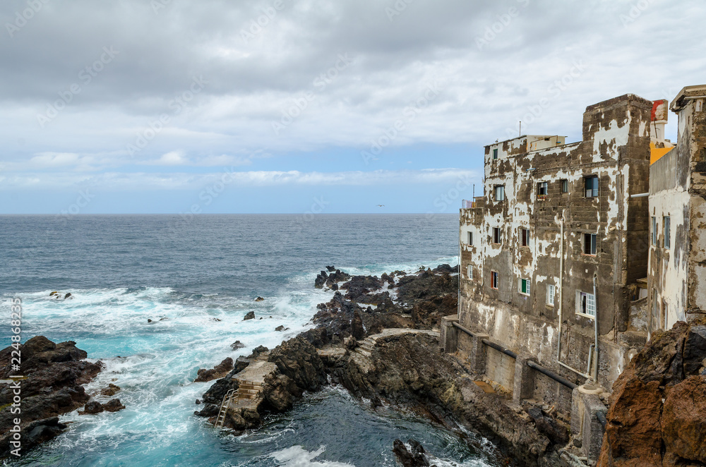 rocky coastline, natural volcanic rock, foaming water and old building