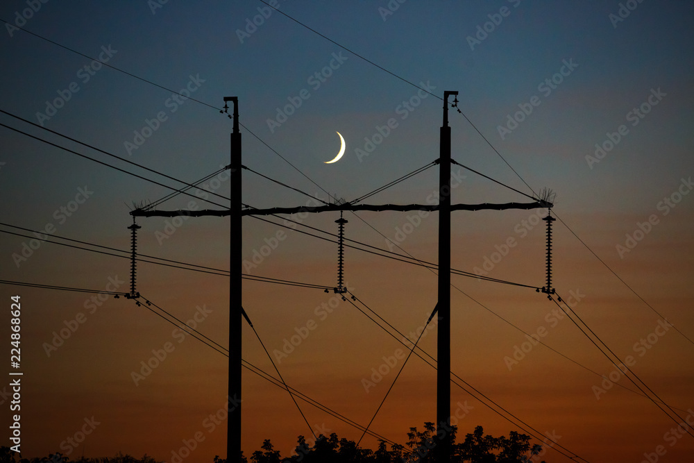 Electrical lines under a night sky with moon.