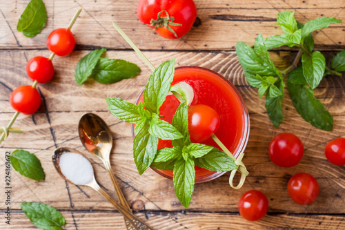 Tomato juice with mint in glass and fresh tomatoes on a wooden table. Healthy organic food concept