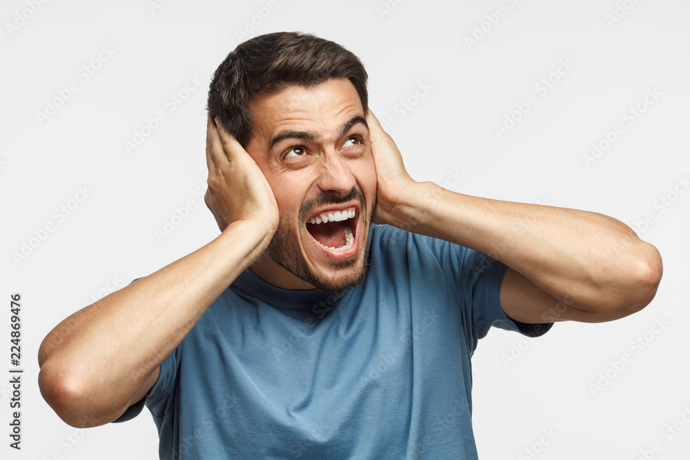 Young man shout at noisy neighbours, stressed by noise, closing ears with both hands, avoid listening fight Young man shout at noisy neighbours, stressed by noise, closing ears with both hands, avoid listening fight
