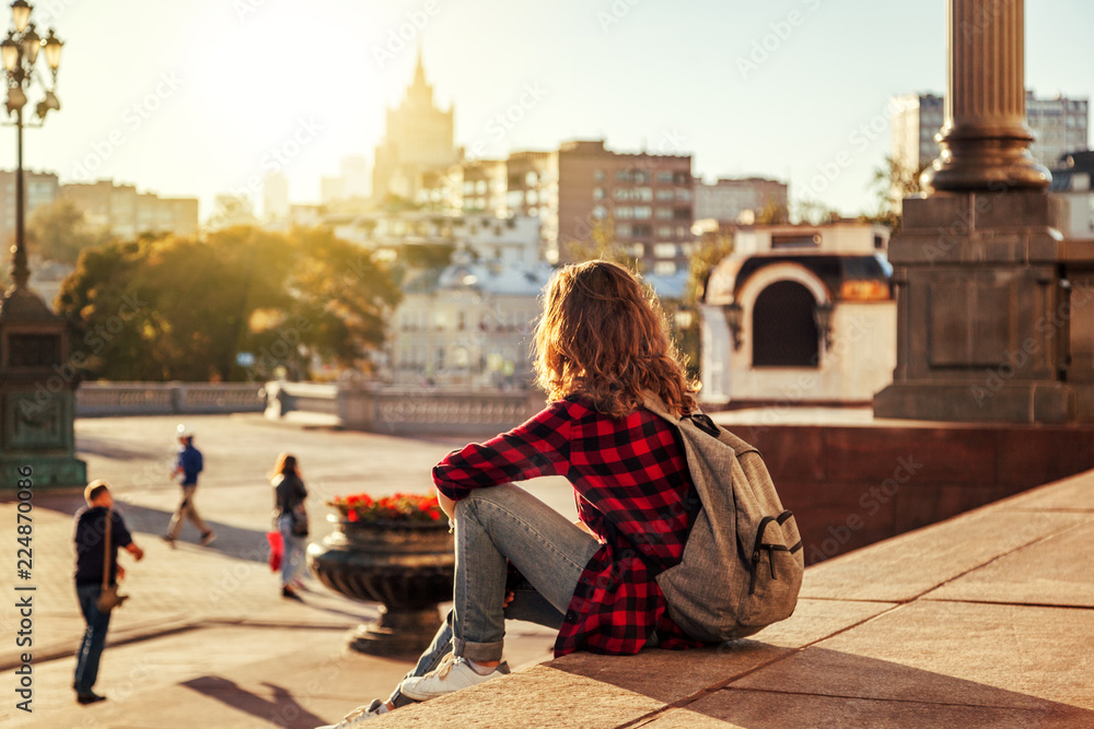 Beautiful woman in the background of a European city in the sun at sunset, student and traveler, vacation in the city, Moscow, Russia