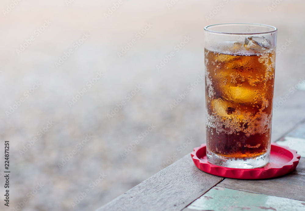glass of cola or coke with ice cubes on a wooden glass of cola or coke with ice cubes on a wooden