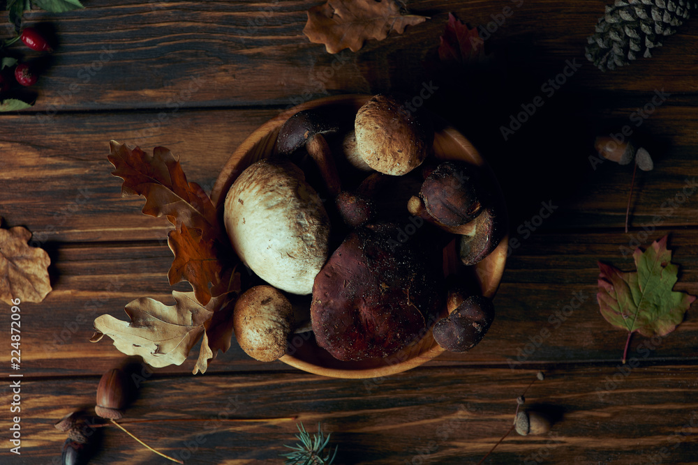top view of fresh picked natural mushrooms in bowl on wooden table