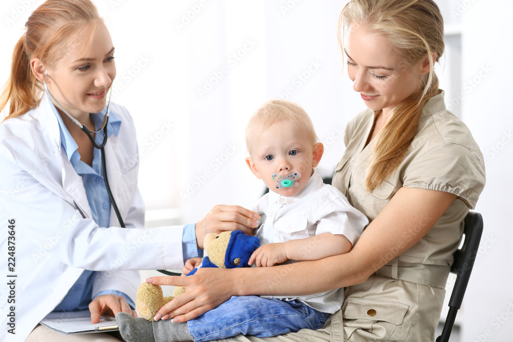 Doctor examining a little boy with stethoscope. Mother holds her son on her lap. Motherless and medicine concept Doctor examining a little boy with stethoscope. Mother holds her son on her lap. Motherless and medicine concept