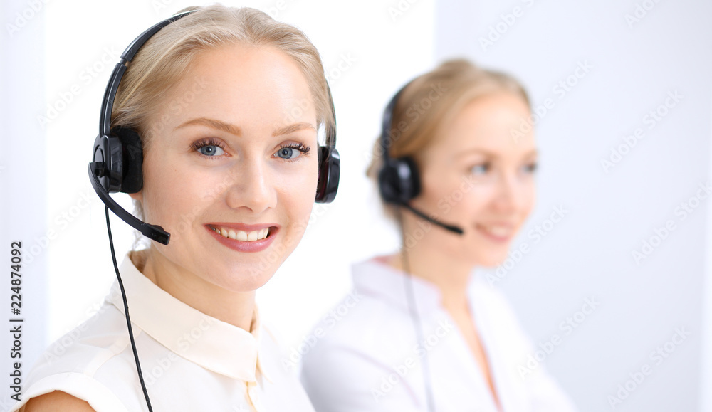 Bright call center office. Two blonde women in a headset Bright call center office. Two blonde women in a headset