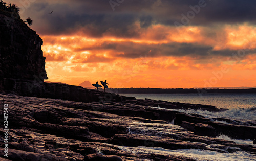 Surfers on shore in sunset time