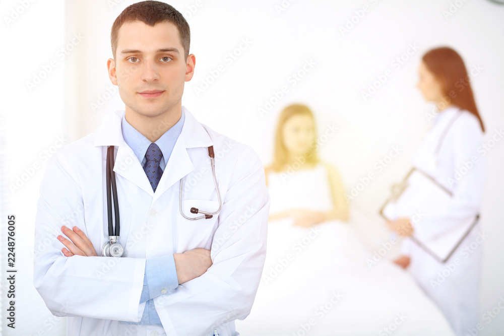 Fototapeta premium Medicine doctor standing and smiling on the background with patient in the bed