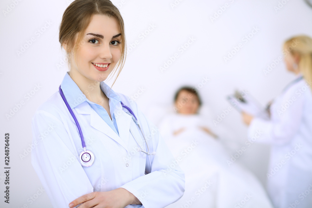 Female doctor smiling on the background with patient and his doctor Female doctor smiling on the background with patient and his doctor