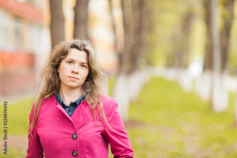 Fall, nature and people concept - Young beautiful woman in pink coat standing in autumn park with copy space Fall, nature and people concept - Young beautiful woman in pink coat standing in autumn park with copy space