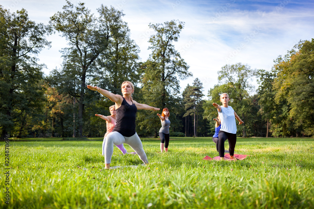 Mixed age group of people practicing yoga outside in the park Mixed age group of people practicing yoga outside in the park