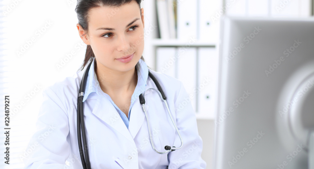 Young brunette female doctor at working place in hospital. Health care, insurance and help concept Young brunette female doctor at working place in hospital. Health care, insurance and help concept