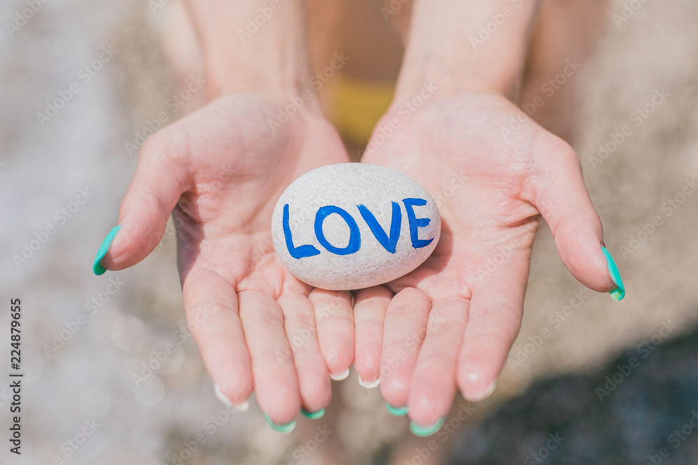 Girl holding in palms round stone pebble with sign love. Girl holding in palms round stone pebble with sign love.