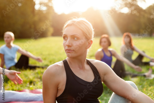 Yoga in the park, middle age woman doing exercises with group of mixed age people © leszekglasner