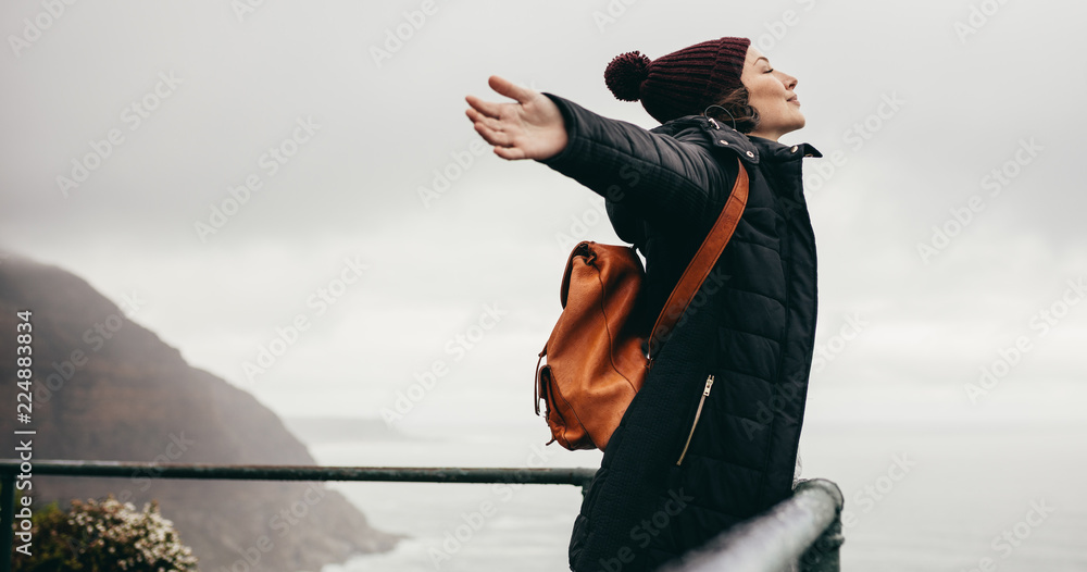 Woman happily breathing in the fresh sea air - obrazy, fototapety, plakaty 