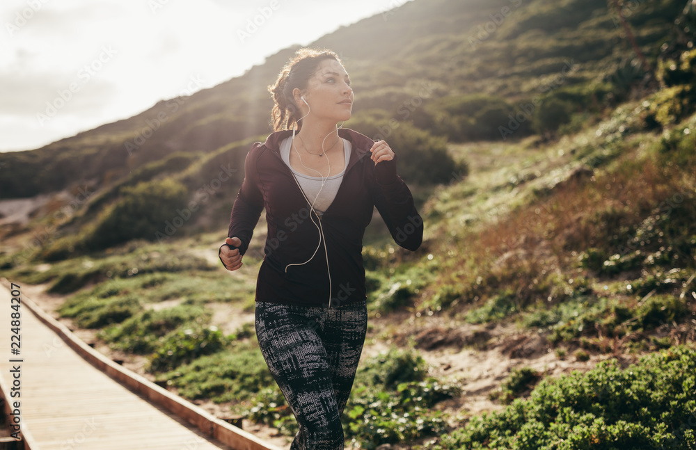 Naklejka premium Woman running on path by the mountain