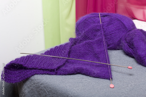 Knitting with steel knitting needles. A ball of purple thread and steel knitting needles in an unfinished knit. © f2014vad