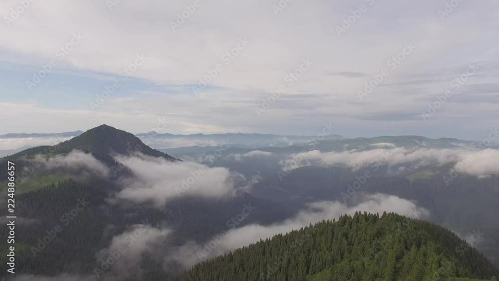 Flight over wooded hills to the mountain ranges in the blue haze on the horizon. Aerial view of Carpathian mountains. Flight over wooded hills to the mountain ranges in the blue haze on the horizon. Aerial view of Carpathian mountains.