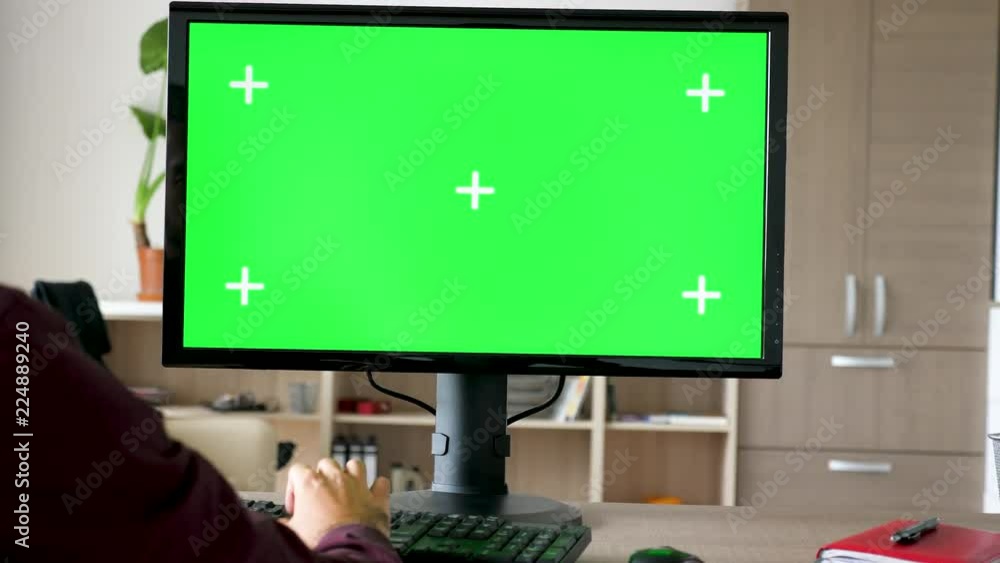Side view of man sitting in front of computer with big green screen mock-up chroma typing on the keyboard. He is in the living room of his house. Dolly slider 4K footage with parallax effect Side view of man sitting in front of computer with big green screen mock-up chroma typing on the keyboard. He is in the living room of his house. Dolly slider 4K footage with parallax effect
