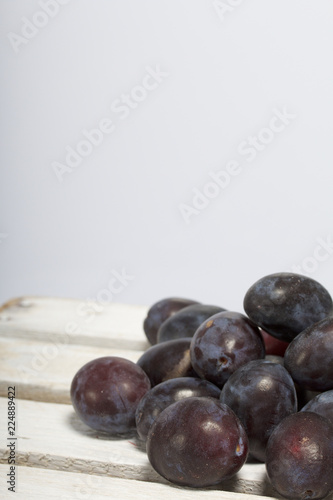 Ripe aromatic plums. Located on a wooden box, knocked out of the boards.