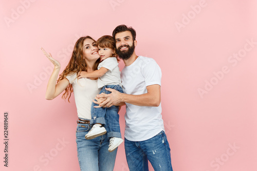 A happy family on pink studio background. The father, mother and son posing together © master1305