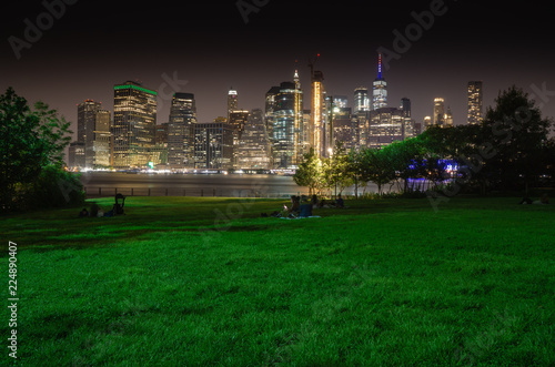 Long time exposure of New York City Manhattan downtown skyline at night viewed from Brooklyn Bridge park
