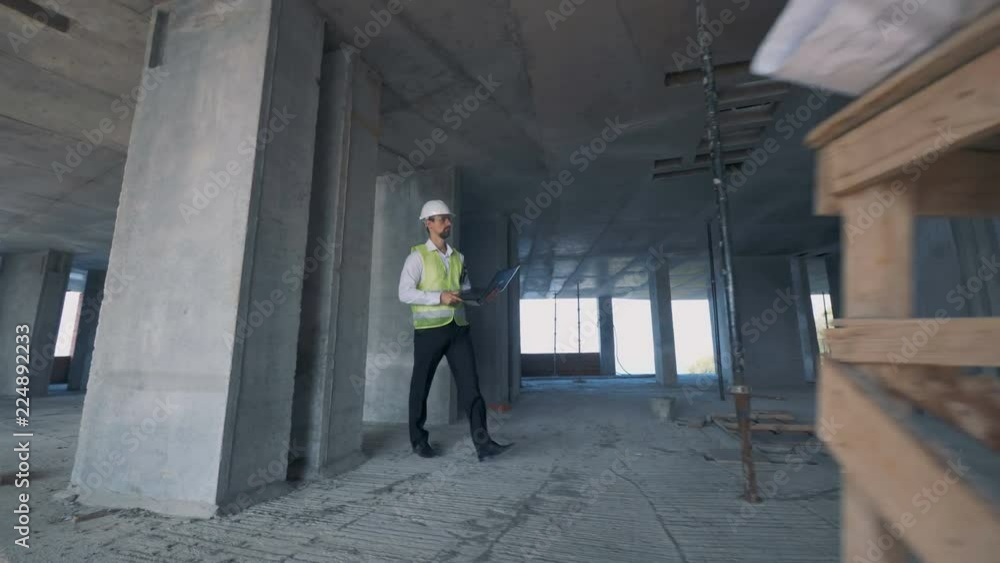 Male building inspector is walking fast across the construction site Male building inspector is walking fast across the construction site