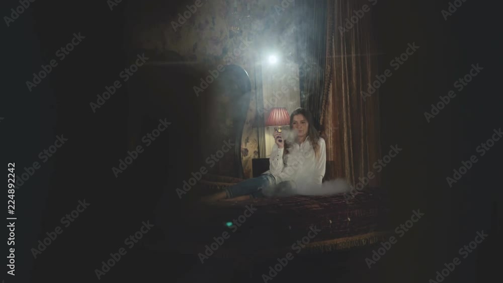 Passionate girl in shirt relaxing on a bed and smoking e-cigarette Passionate girl in shirt relaxing on a bed and smoking e-cigarette