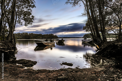 Fishing boats on country river surrounded by trees