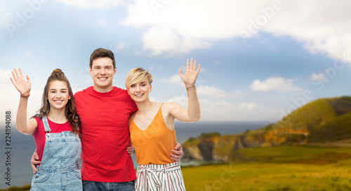 travel, tourism and summer holidays concept - group of happy smiling friends hugging over big sur coast of california background © Syda Productions