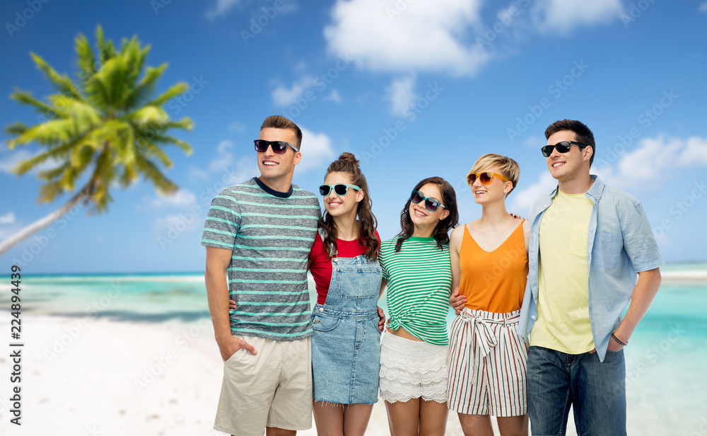 travel, summer holidays and tourism concept - group of happy smiling friends in sunglasses hugging over tropical beach background in french polynesia