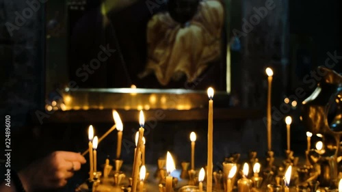 Woman lights a wax candle in a censer in an Orthodox Catholic ancient temple photo