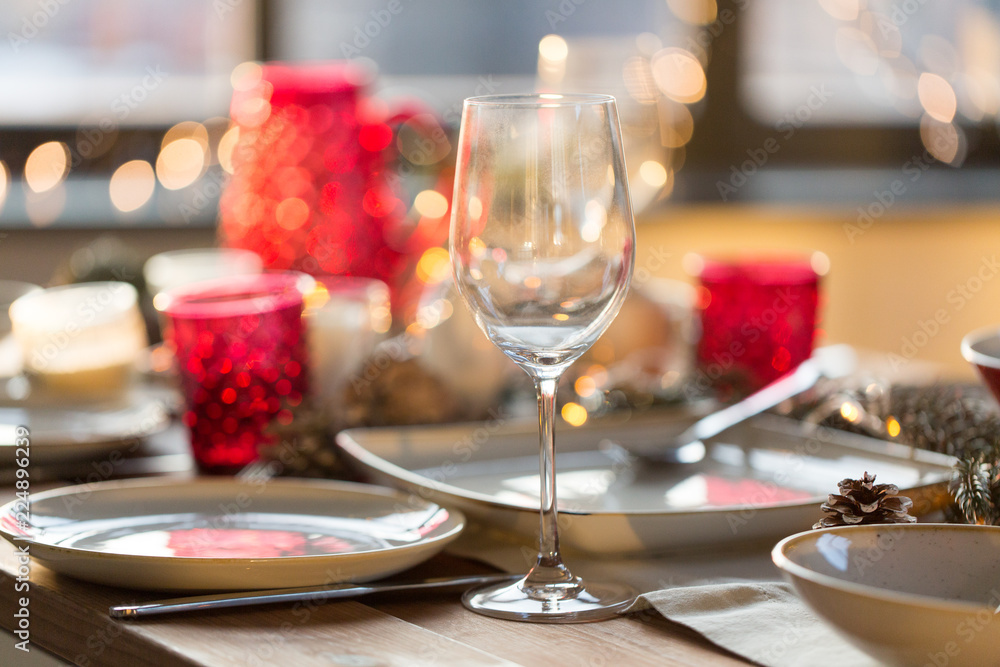 christmas, holidays and table setting concept - wine glass and tableware for festive dinner at home