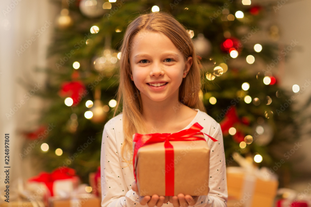 christmas, holidays and childhood concept - smiling girl with gift box at home christmas, holidays and childhood concept - smiling girl with gift box at home