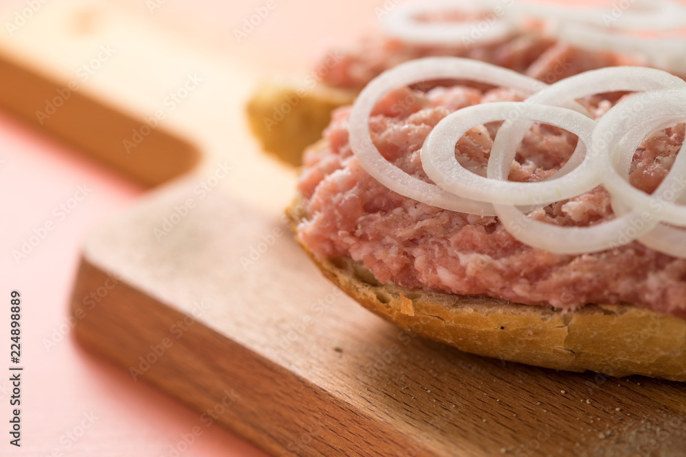 Schweine Mettbrötchen mit Zwiebeln auf Holzbrett Schweine Mettbrötchen mit Zwiebeln auf Holzbrett