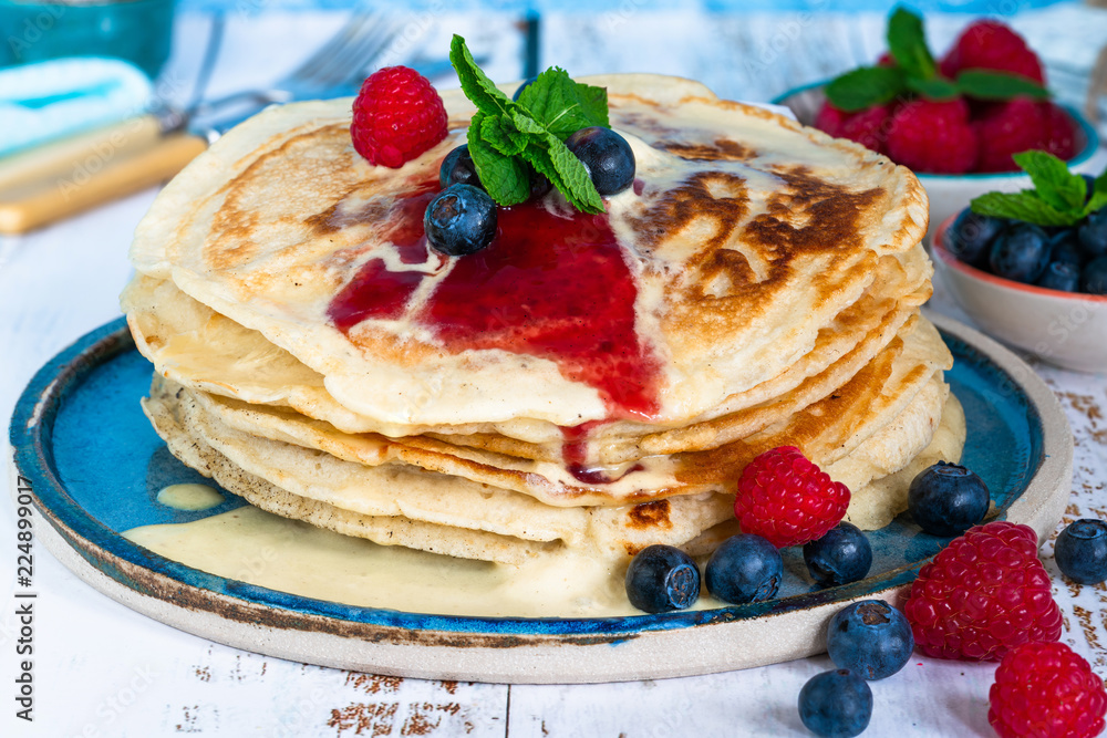 A stack of pancakes with fresh fruit, jam and cream on a plate A stack of pancakes with fresh fruit, jam and cream on a plate