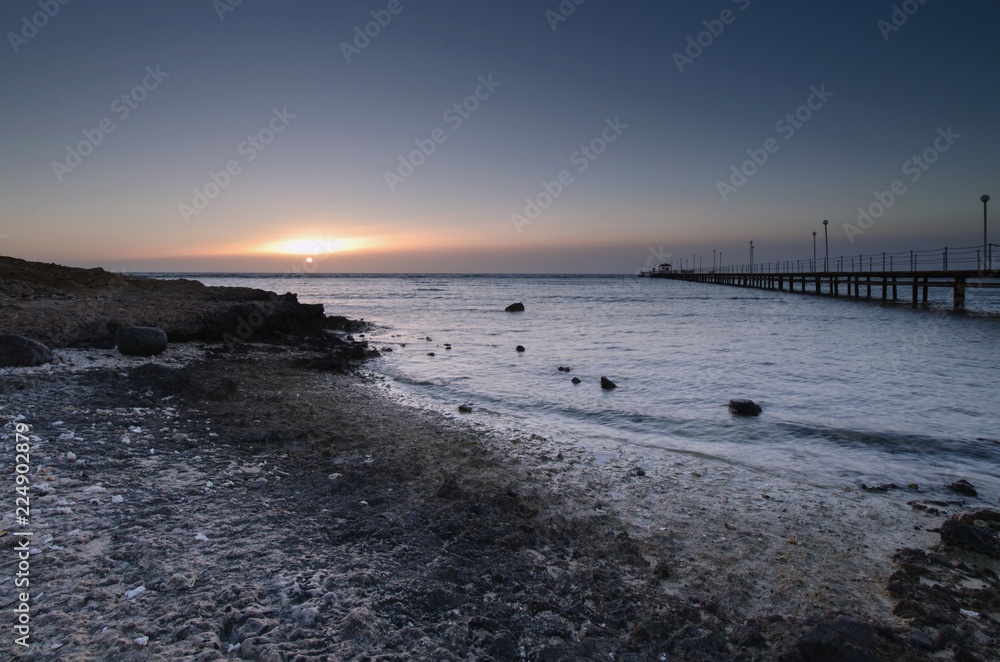 Obraz premium Sunrise over the sea and a light wooden pier.