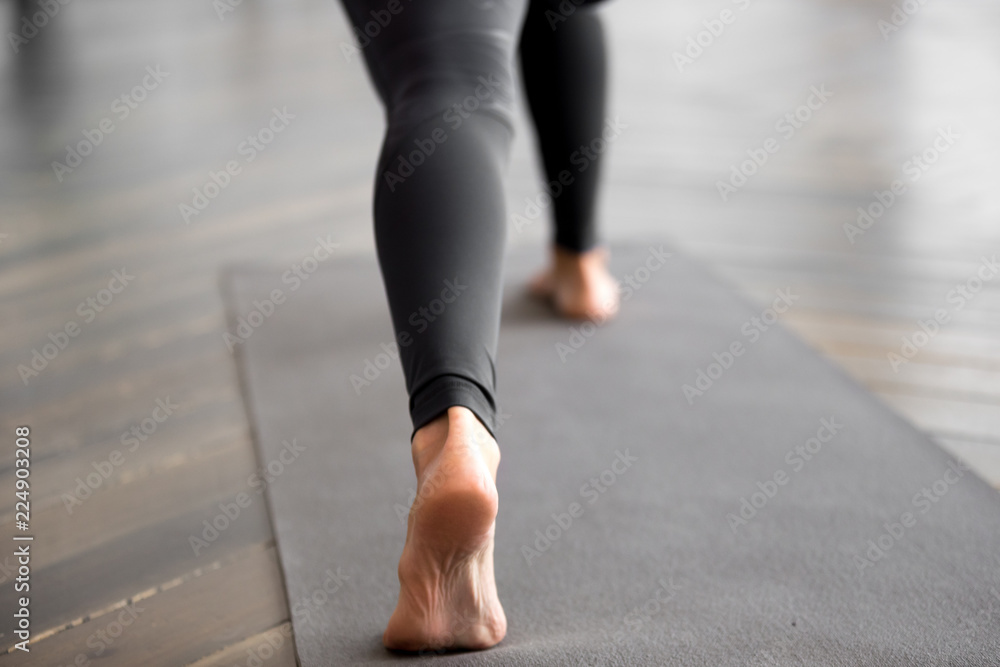 Sporty woman practicing fitness, doing exercise, yoga pose, working out on yoga mat, wearing sportswear black pants, indoor close up, at yoga studio, focus on a heel. Well being, healthy life concept Sporty woman practicing fitness, doing exercise, yoga pose, working out on yoga mat, wearing sportswear black pants, indoor close up, at yoga studio, focus on a heel. Well being, healthy life concept