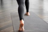 Sporty woman practicing fitness, doing exercise, yoga pose, working out on yoga mat, wearing sportswear black pants, indoor close up, at yoga studio, focus on a heel. Well being, healthy life concept