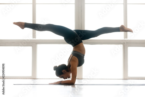Fototapet Young yogi attractive woman practicing yoga, doing Pincha Mayurasana exercise, h