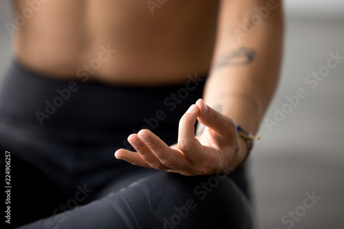Young sporty yogi yoga woman meditating doing Easy Seat exercise  Sukhasana pose with mudra  working out  indoor hand close up  at yoga studio  focus on fingers. Hobby wellbeing activity concept