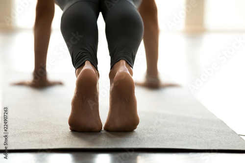 Young sporty beautiful woman practicing yoga, doing Push ups or press ups exercise, phalankasana, Plank pose, working out, wearing sportswear, indoor close up, at yoga studio photo