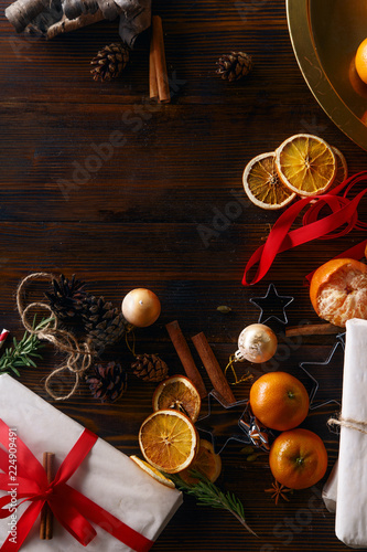 Christmas atmoshpere flatlay. Overhead view. Gingerbread cookies, tangerines and new year decorations on wooden background